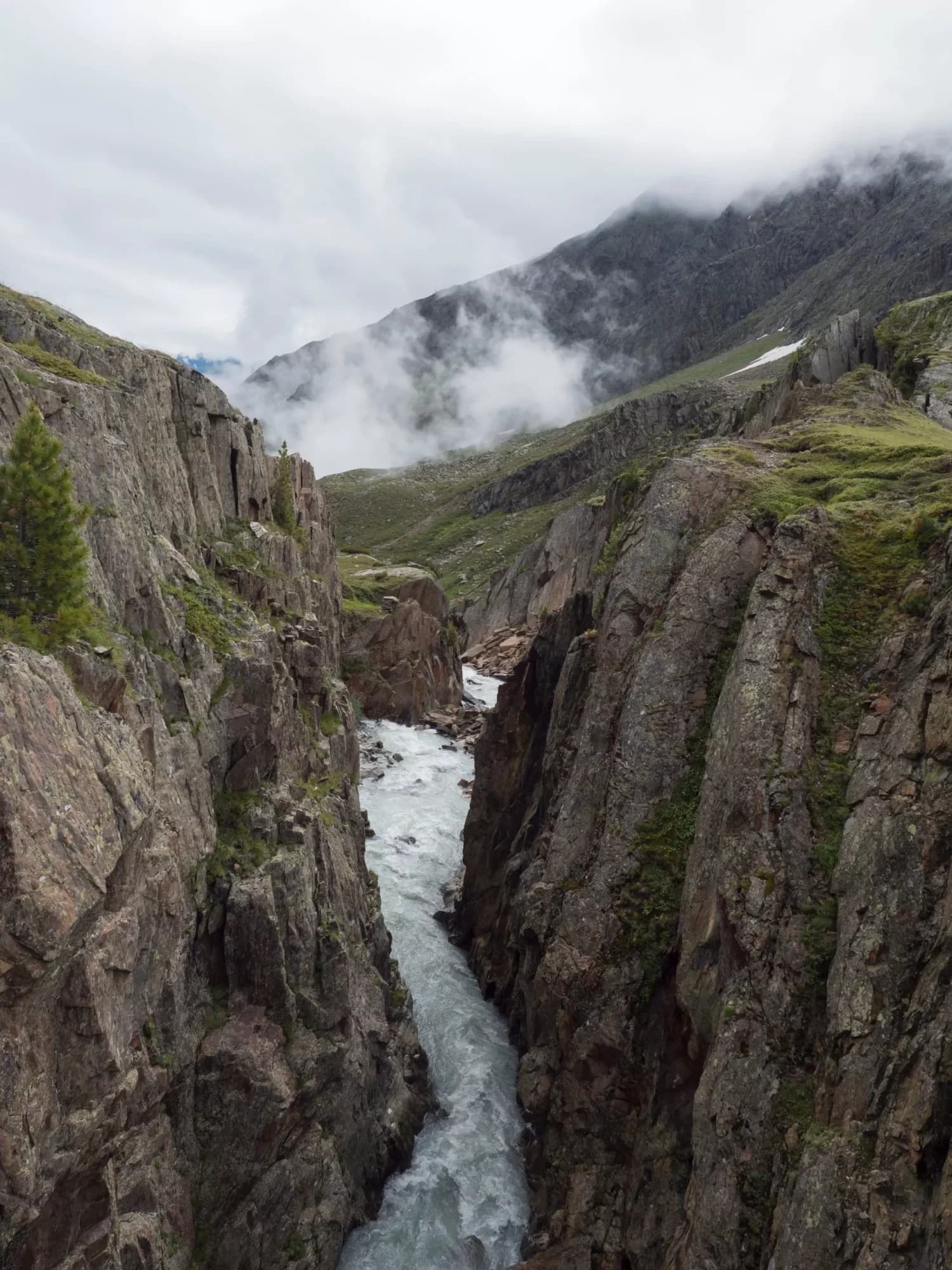 View from footbridge over the wild Fernaubach mountain stream in Tyrol, Austria close to Mittelstation at Stubai. Summer foggy morning.